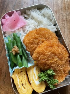 a bento box filled with rice, green beans and fried chicken breast patties