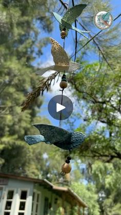 a wind chime hanging from a tree in front of some trees and a house