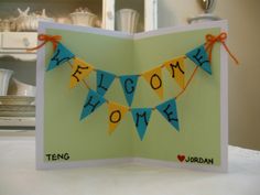 an open card with the words welcome home hanging from it's sides and a bunting banner