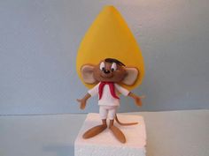 a figurine of a mouse standing on top of a block of white paper