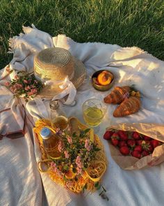 a picnic with strawberries, lemonade and other food items laid out on a blanket