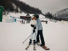 two people hugging each other on skis in the snow