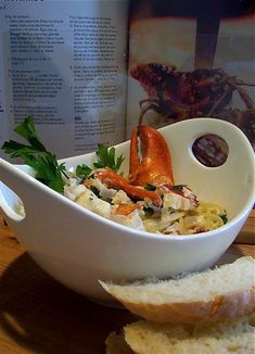 a white bowl filled with food next to a slice of bread on top of a table