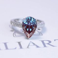 a blue and white diamond ring sitting on top of a piece of paper