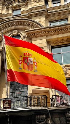 the spanish flag is flying in front of an old building