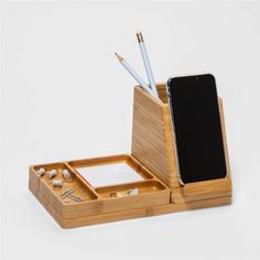 a cell phone and pen holder on a white surface with two pencils in it