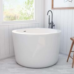 a large white bath tub sitting in a bathroom next to a wooden chair and window