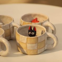 three coffee mugs with faces painted on them sitting on a table next to each other