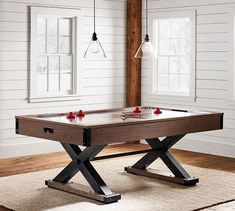 a pool table in the middle of a room with white walls and wood flooring