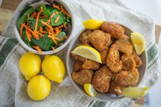 two bowls filled with food next to some lemons and carrots on a towel