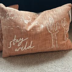 two decorative pillows with the words stay wild printed on them, sitting on carpeted floor