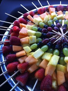 an assortment of fruits arranged on skewers in a circular arrangement with strawberries, grapes, and melon