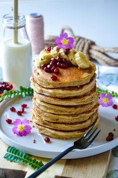 a stack of pancakes topped with bananas and pomegranates on a plate