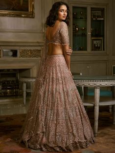 Editor's Note The set includes a dust pink shimmer tulle lehenga that is embroidered with zardozi crystal work, which is then paired with an embellished choli and dupatta. The intricate embroidery and shimmering fabric are sure to make a stunning impression. Color: Dust pink Fabric: Shimmer tulle Components: Lehenga, blouse and dupatta Occasion: Reception and wedding Disclaimer: Product color may slightly vary due to photographic lighting sources or your monitor setting. Care: Dry clean only Abo Shimmer Lehenga, Tulle Lehenga, India Wedding Dress, Dolly J, Reception Outfits, Crystal Work, Walima Dress, Dust Pink, Indian Outfits Lehenga