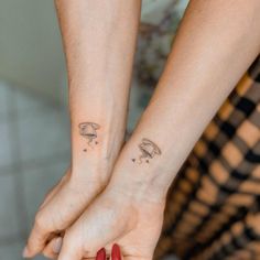 two people holding hands with tattoos on their wrist and one has a mushroom tattoo on the other hand