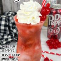 a red drink with whipped cream and cherries in it next to a soda can