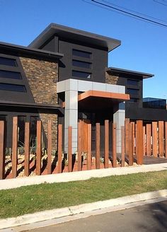 a large black building with wooden fence around it's perimeter and grass on the sidewalk