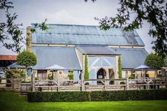 the building has many tables and umbrellas on it's front lawn, along with some trees