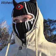 a person wearing a black and white hooded jacket with a red eye on it's face