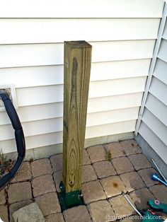 a wooden post sitting on top of a brick patio next to a building with tools around it