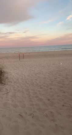 two people are playing frisbee on the beach at sunset or dawn with an ocean in the background