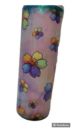 a purple and blue vase with flowers painted on the side, sitting in front of a white background