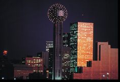 the city skyline is lit up at night with fireworks in the sky and lights on