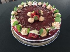 a chocolate cake with strawberries and cream on top is sitting on a black table