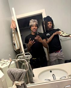 two men standing in front of a bathroom mirror