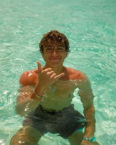 a young man in the water making a peace sign