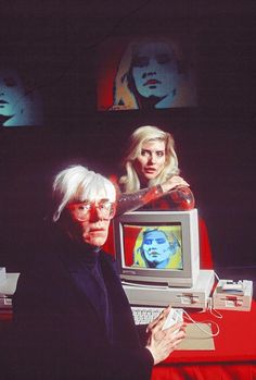 an old man and woman sitting in front of a computer monitor with the screen turned on