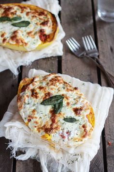 two small pizzas sitting on top of napkins with silverware next to them