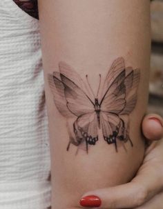 a woman's arm with a butterfly tattoo on the left side of her arm