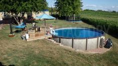 an above ground swimming pool in the middle of a yard with people sitting around it