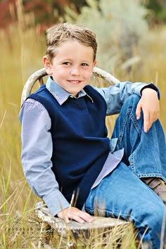 a young boy sitting on top of a wooden log in the middle of tall grass