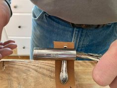 a man is working on an object with wood and silverware in his hands,