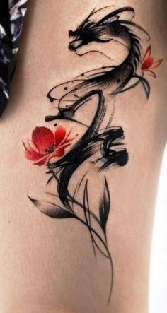 a woman's thigh with a dragon and flower tattoo design on the side of her leg