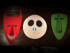 three paper masks with faces on them sitting next to each other in front of a wooden table