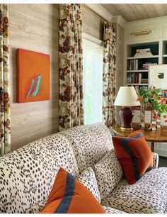 a living room filled with furniture and lots of windows covered in animal print drapes