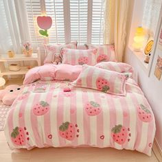 a pink and white striped bed with strawberrys on the comforter, pillows and pillow cases