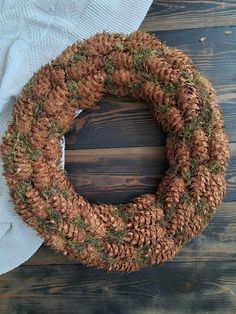 a pine cone wreath on top of a wooden table next to a white towel and napkin