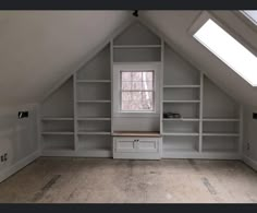 an empty room with some shelves in the corner and a skylight above it that is partially open