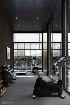 a gym with treadmills, exercise bikes and other equipment in front of large windows