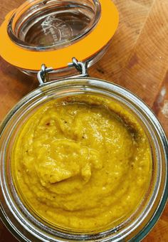 a jar filled with yellow mustard sitting on top of a wooden table