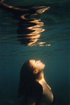 a woman is swimming in the water with her head above the water's surface