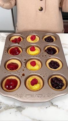 a muffin tin filled with cupcakes covered in jelly and raspberries