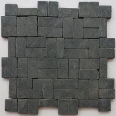 a close up of a wall made out of small gray bricks and cement blocks on the floor