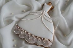 a decorated cookie in the shape of a bride's dress on a white fabric