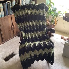 a black and white blanket sitting on top of a chair next to a book shelf