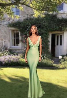 a woman standing in front of a house wearing a green dress